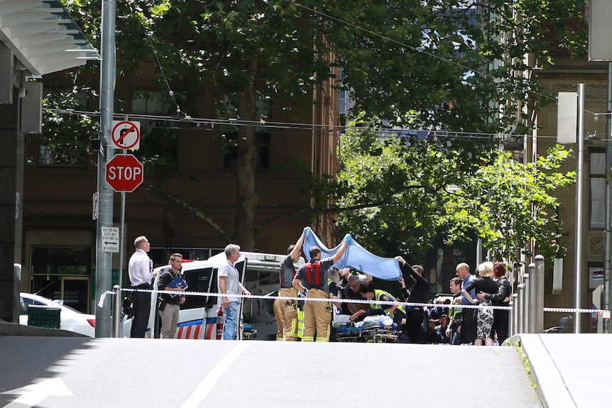 Emergency services work on a person on Bourke Street.