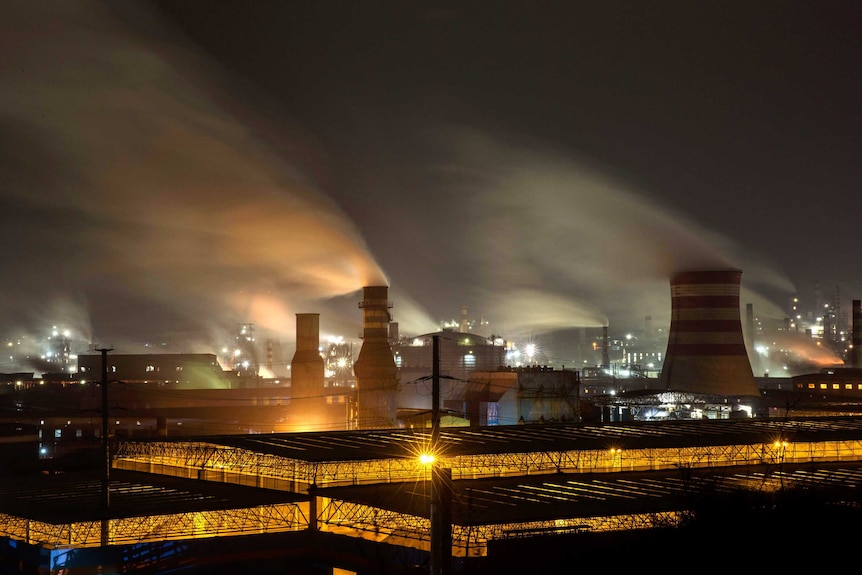 Factories emitting smoke at night.