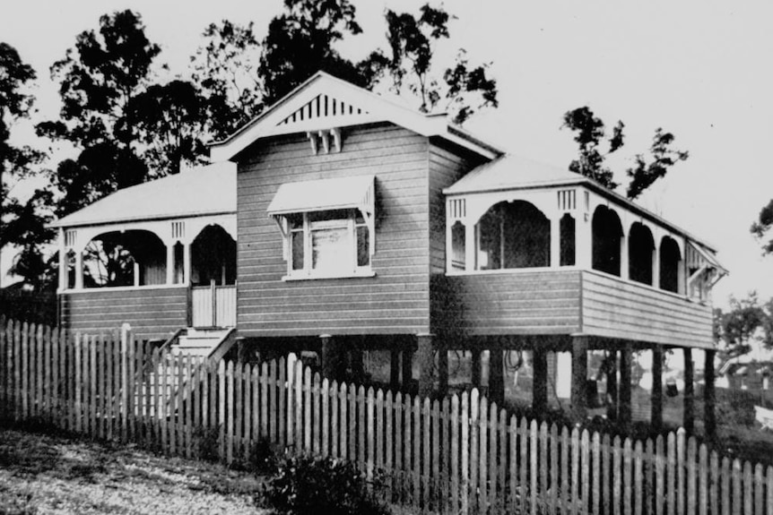 A black and white photo of a Queenslander home on stilts. 