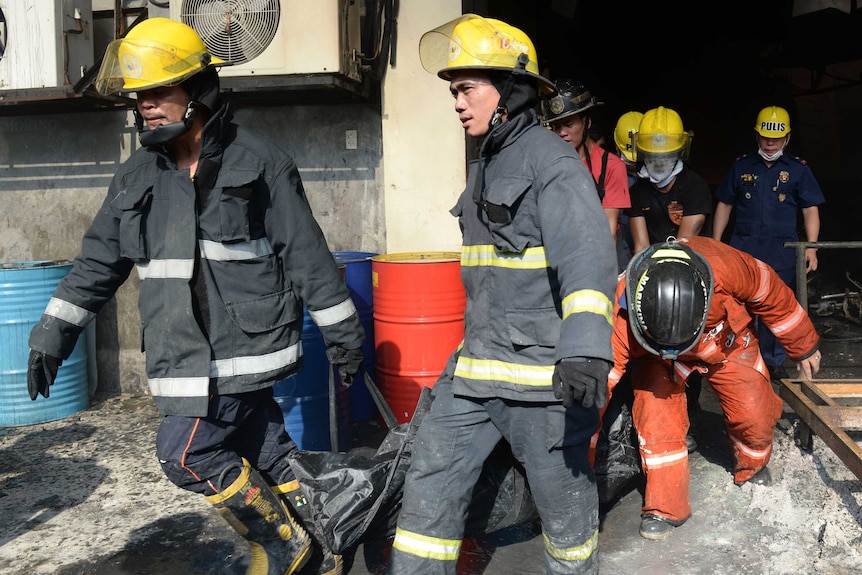 Philippine firemen carry bags containing the bodies of victims of the factory fire