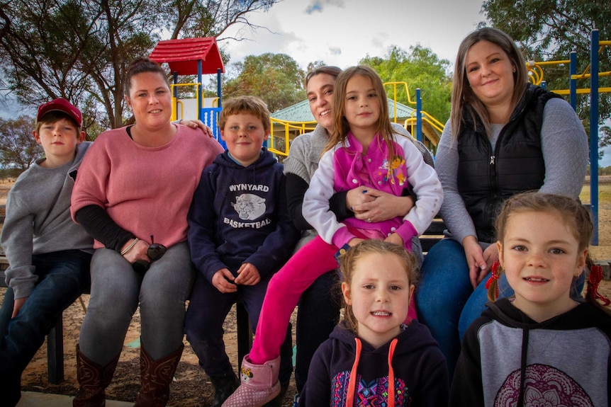 Mothers and children sit together in a playground.