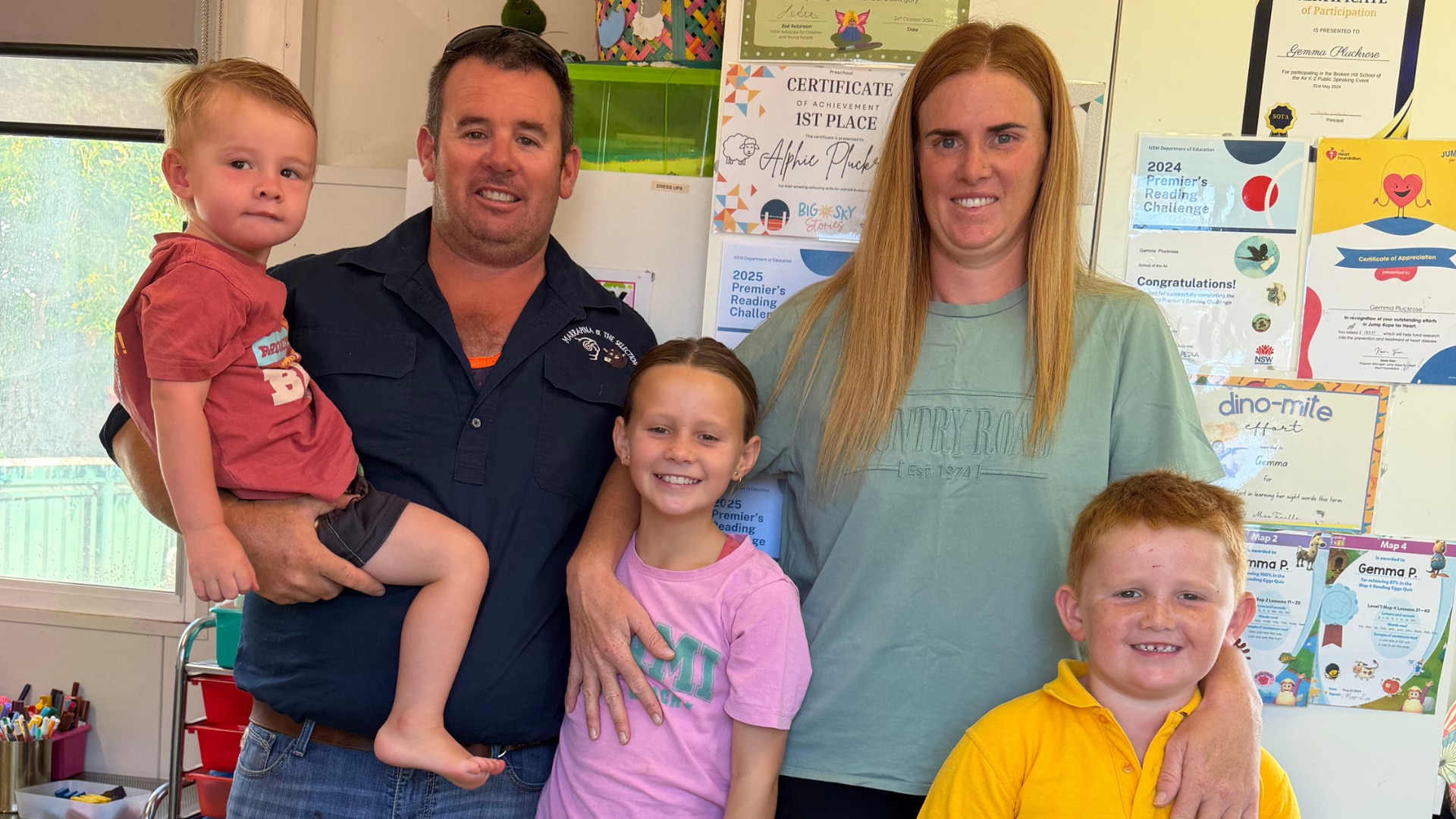 An adult man and woman standing with their arms around two young boys and a young girl