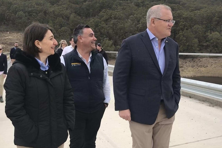 three people on the walkway of a rural dam