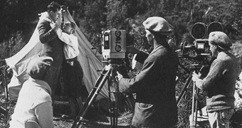A black and white photo of people making a film in the early 1900s