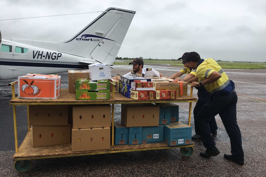 Chartair employees load supplies onto a plane heading out bush