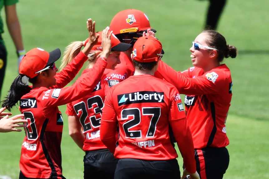 A group of women wearing red give each other high fives