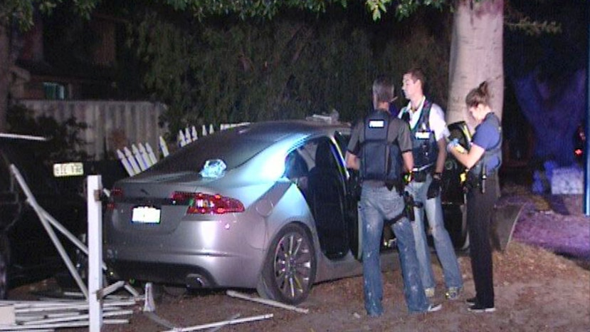 A luxury silver sedan with its doors open and police officers nearby after crashing into a tree in Carlisle.