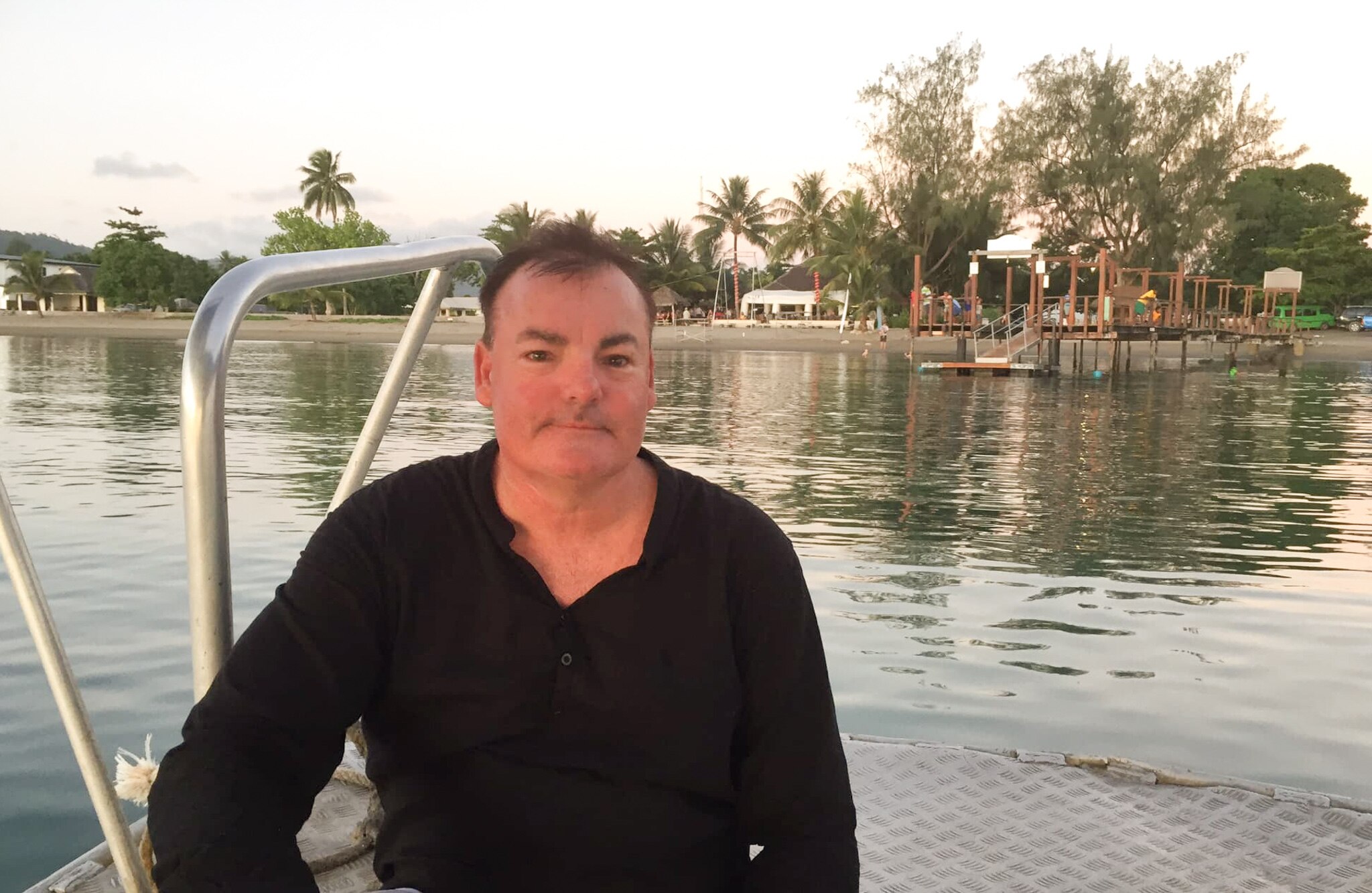 A close up of a man with brown hair smiling in a grey suit.