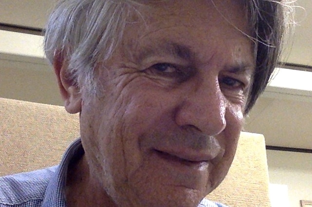 A close up of the face of an older man with grey hair who is smiling.