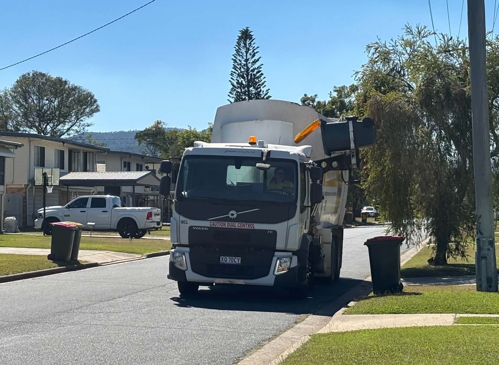 A rubbish truck empties a recycling bin on a street