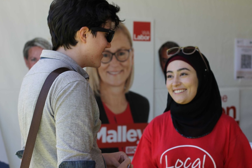 Young Labor female volunteer chatting to student inside tent