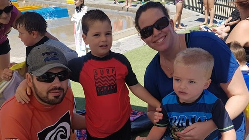 Kylie Hicklin poses for a photo at a birthday party with her husband and two young sons