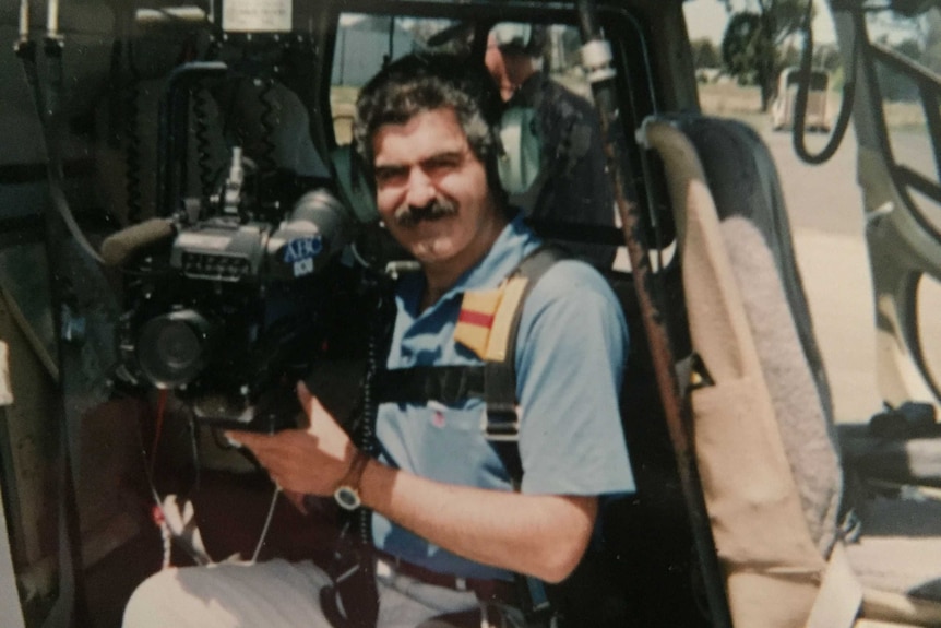 Tucci sitting in chopper with camera and headphones on.