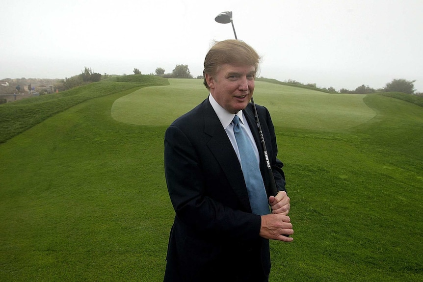 Donald Trump posing with a golf club in 2002