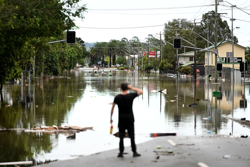A man looks at a flooded street 