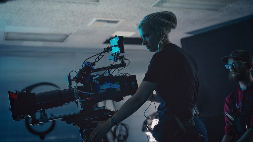 Halyna Hutchins on a film set operating a large camera.