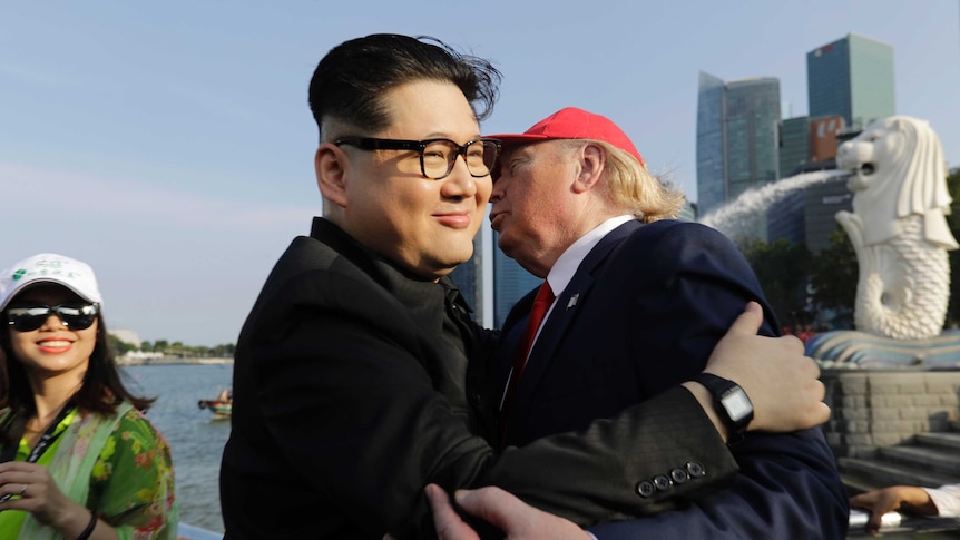 A tourist looks on as Kim Jong Un and Donald Trump impersonators embrace