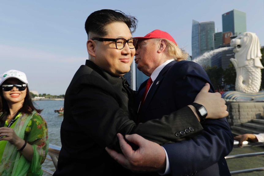 A tourist looks on as Kim Jong Un and Donald Trump impersonators embrace