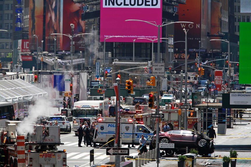 A wide shot shows authorities surrounding a crashed car in Times Square.