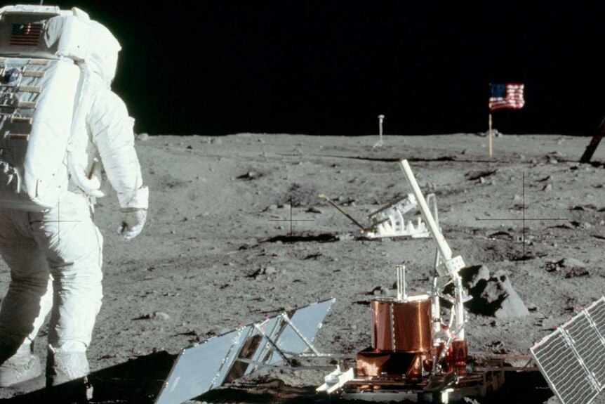 Neil Armstrong's photograph showing Buzz Aldrin setting up experiments, with the flag and TV camera in the distance.