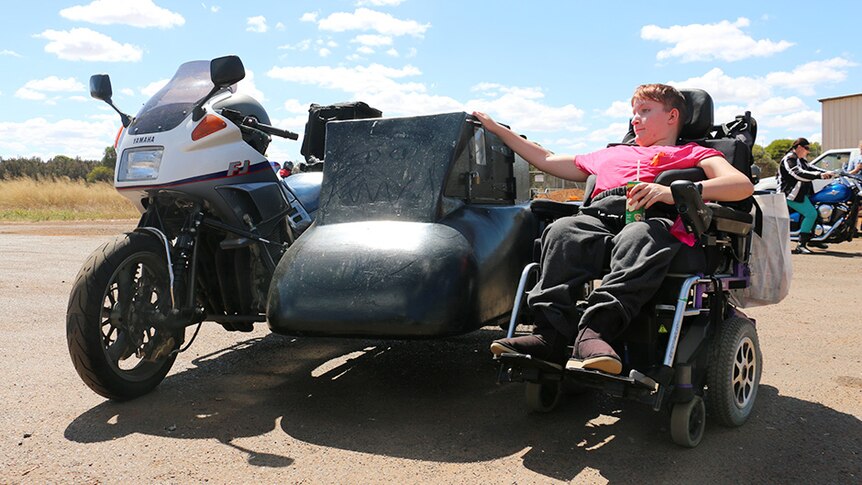 Katanning teenager Shanniah Barker sits in her wheelchair with an arm resting on her father's motorbike side pod.
