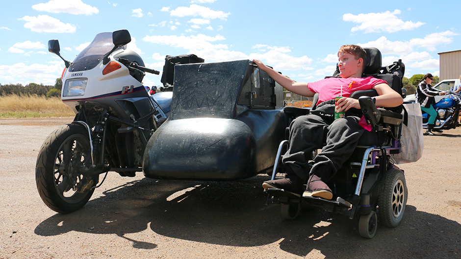 Katanning teenager Shanniah Barker sits in her wheelchair with an arm resting on her father's motorbike side pod.