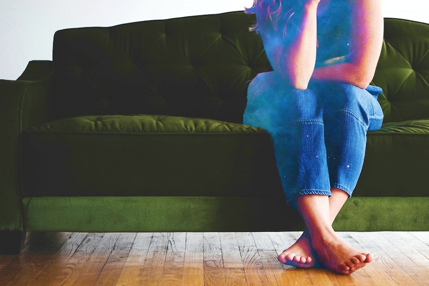 Woman sitting on a green couch looking lonely.