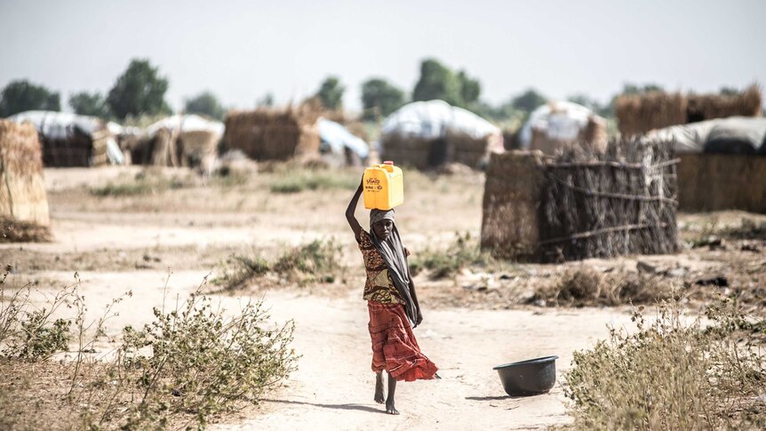 A girl walks to collect water from a Save the Children water point in the informal displacement camp at Musari