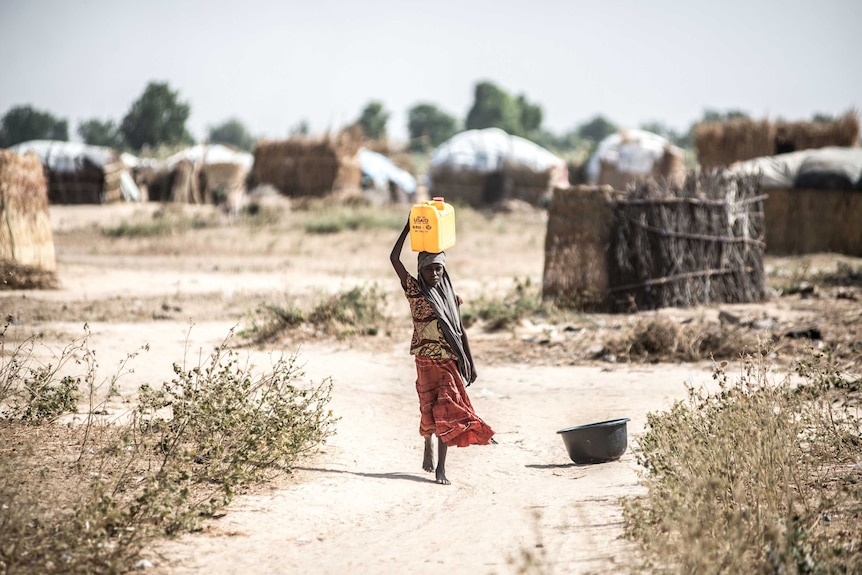 A girl walks to collect water from a Save the Children water point in the informal displacement camp at Musari