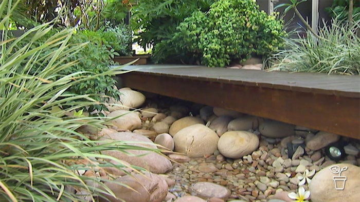 Timber walkway covering large pebbles in garden