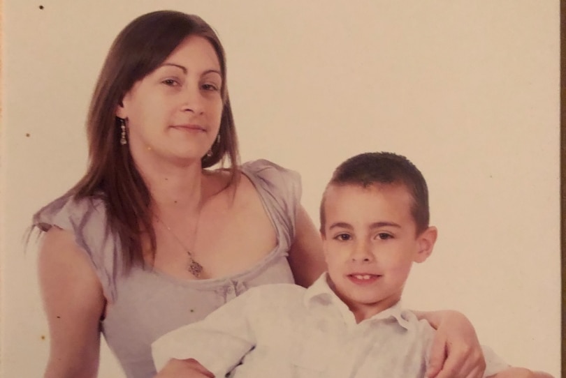 A faded photo of a beautiful young woman and her young son leaning on her