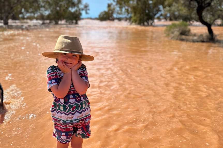 A little girl stands in front of a flooding creek.