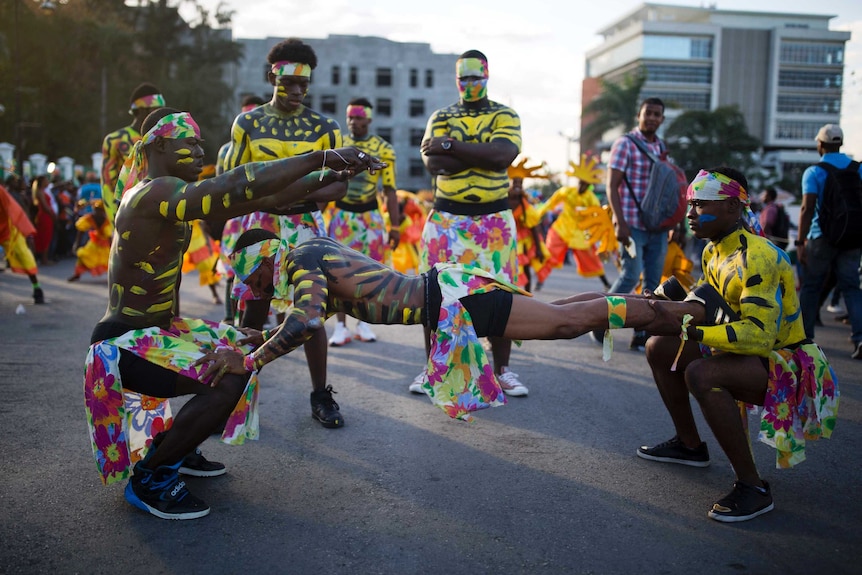 Men in body paint and multicoloured costumes perform in the street during Carnival in Haiti.