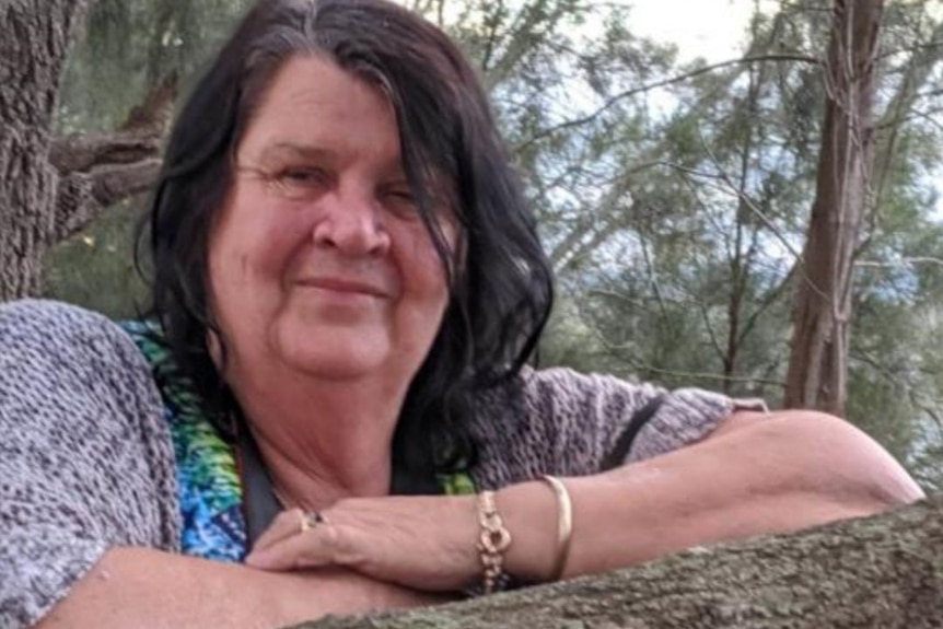 A woman leaning over a horizontal tree branch