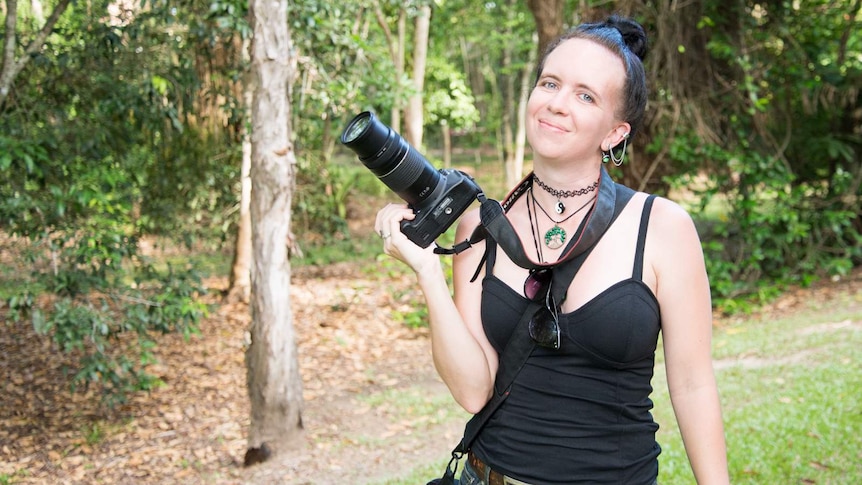 Amateur photographer Simone Vinton holds her camera in one hand and smiles for a photograph.
