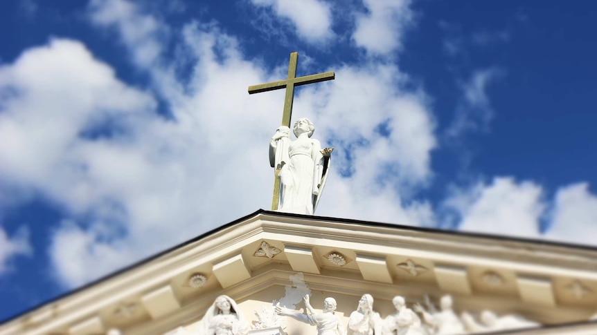 high angle shot of cross and saint on church roof