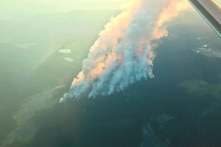 Plumes of smoke rise from a ridge around a lake as fierce fires burn