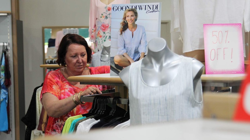 A photo of businesswoman Joy Passmore looking through garments in her store.