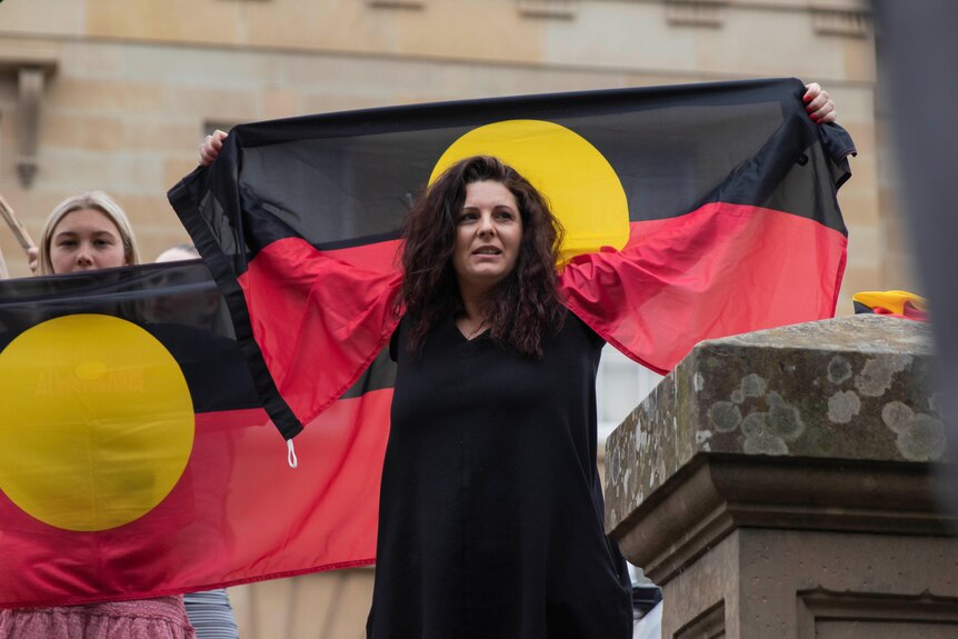 A woman drapes an Aboriginal flag around her shoulders