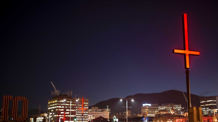 An bright red inverted cross mounted on a pole at night in Hobart