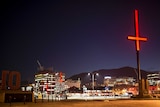 An bright red inverted cross mounted on a pole at night in Hobart