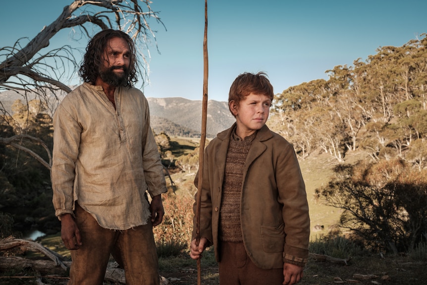 An Aboriginal man and a boy looking off into the distance.