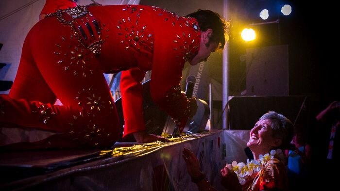 An Elvis impersonator serenades a woman.