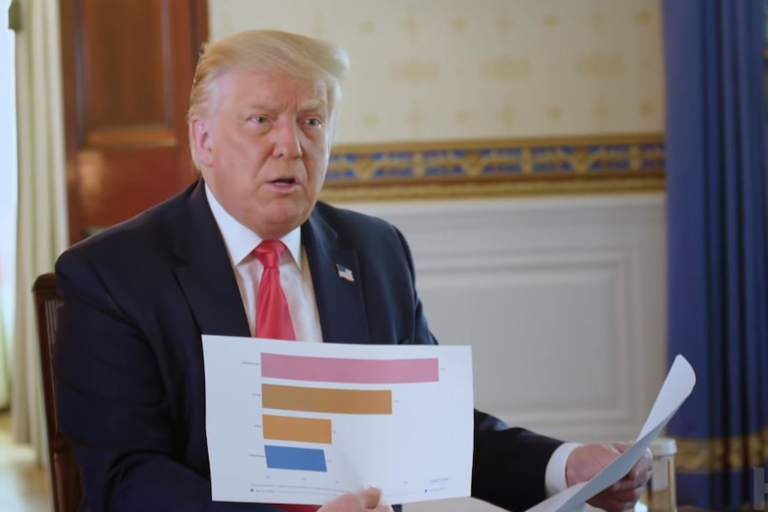 A man sitting down showing a graph on a piece of paper.