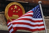 United states flag next to a Chinese emblem.