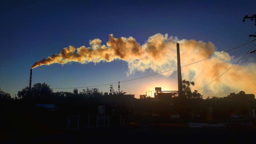 An industrial stack belching smoke over a town.