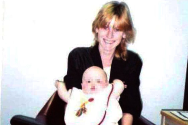 Tracey smiling with a baby in her lap.