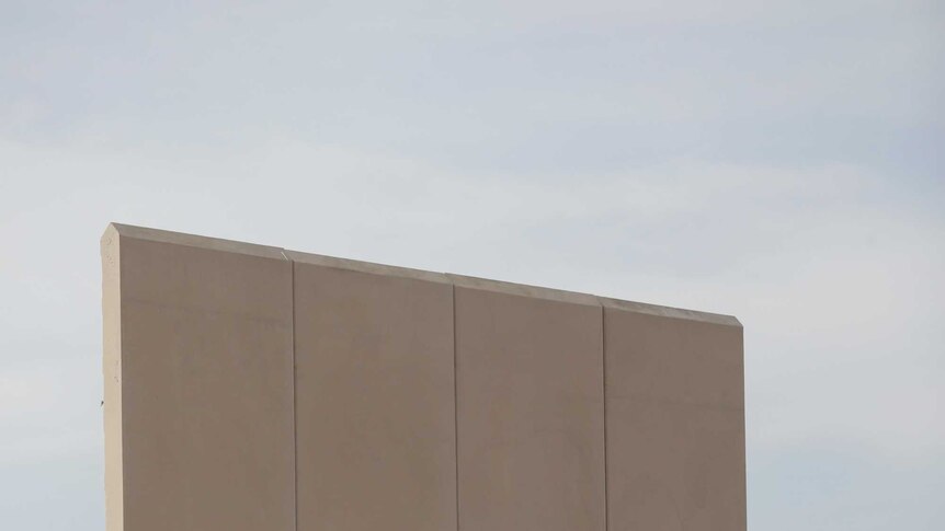 Tan concrete wall is thick at the bottom and narrows considerably toward the pointed top.