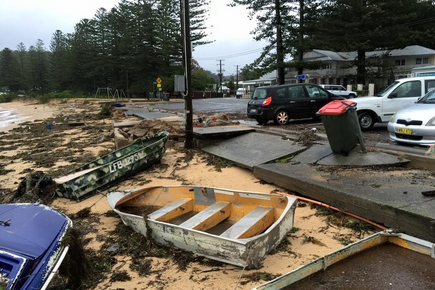 Small boats damaged by storms strewn up near the road at Patonga beach on New South Wales central coast