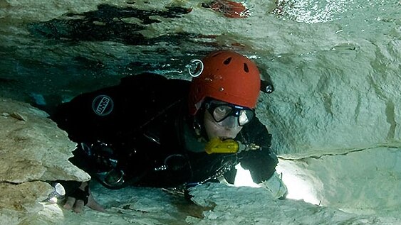 Tight Squeeze for a scuba diver in a flooded cave